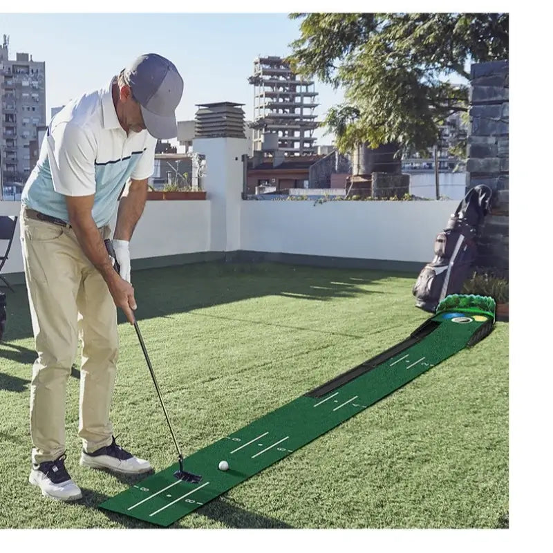 A golfer practicing on a Golf Putting Green mat outdoors with a ball return feature.