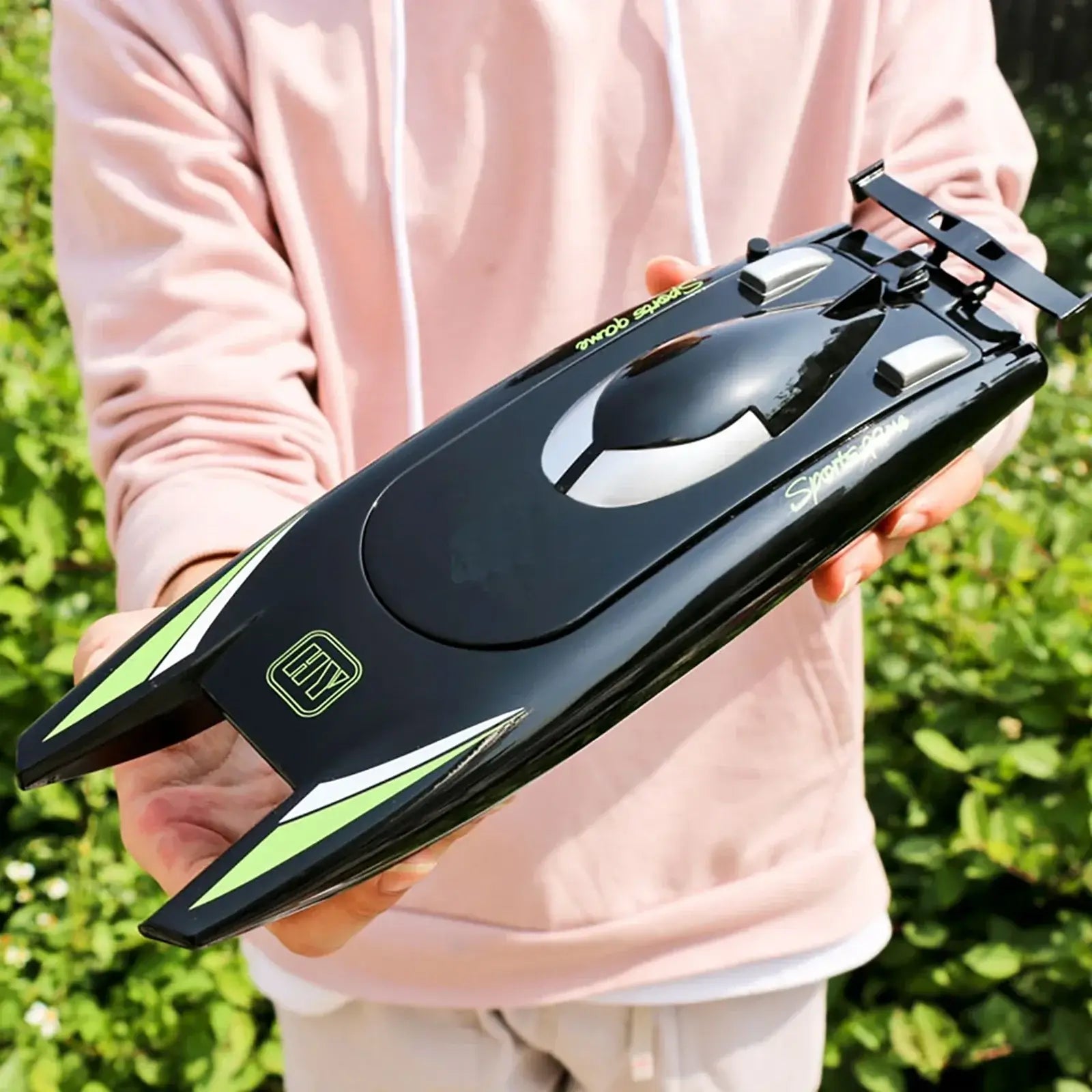 Person holding an RC Boat 2.4Ghz 25kmh high-speed remote control racing ship in a sunny outdoor setting.