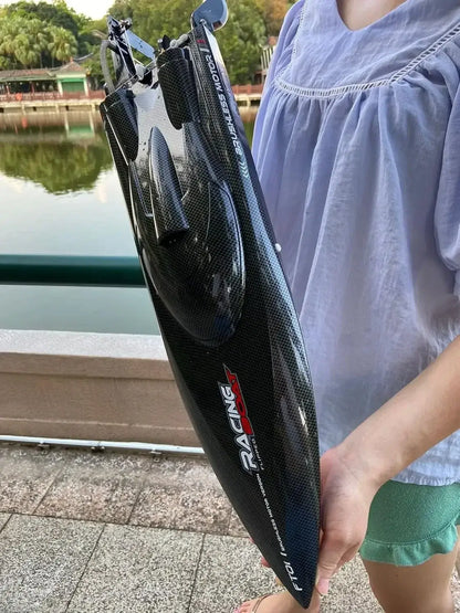   High Speed RC Boat 55km FT011 held by a person near water with a sleek carbon fiber design.