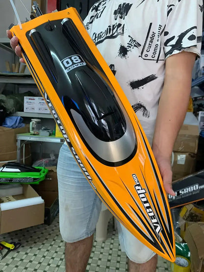 Person holding the SR80 Pro. RTR 31.5 RC Boat in orange and black design, showcasing the sporty remote control boat.