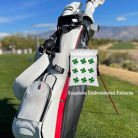 Golf valuables pouch with embroidered clover design hanging from a golf bag on the course.