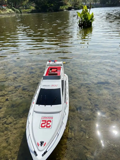 Super large remote control yacht floating on a lake with clear water and greenery in the background.