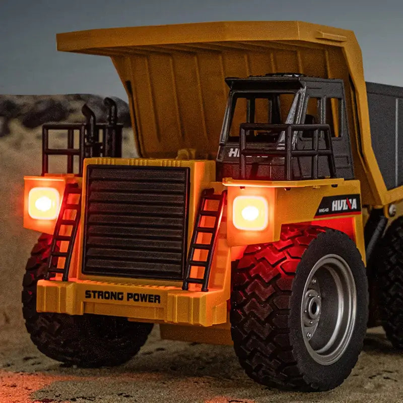 Huina 533D Alloy Remote Control Dump Truck with lights on a sandy surface.