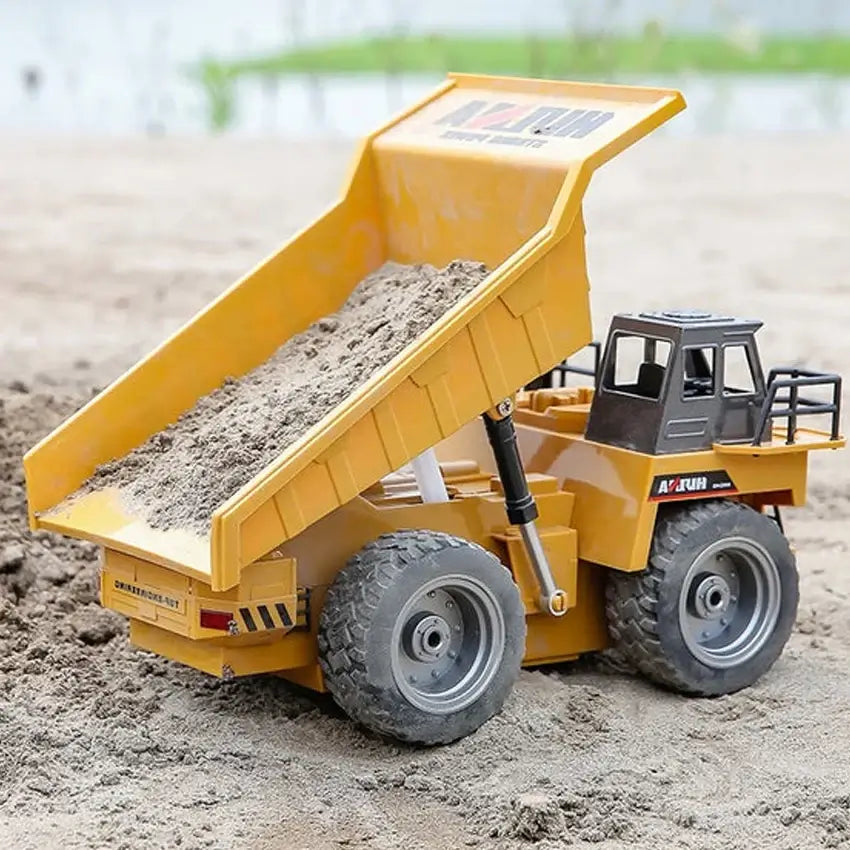 Huina 1534 Rc Truck Tractor loading sand in a remote control dump truck on a sandy surface.
