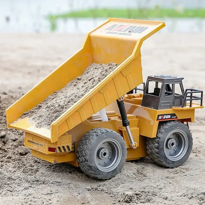 Huina 1534 Rc Truck Tractor loading sand in a remote control dump truck on a sandy surface.