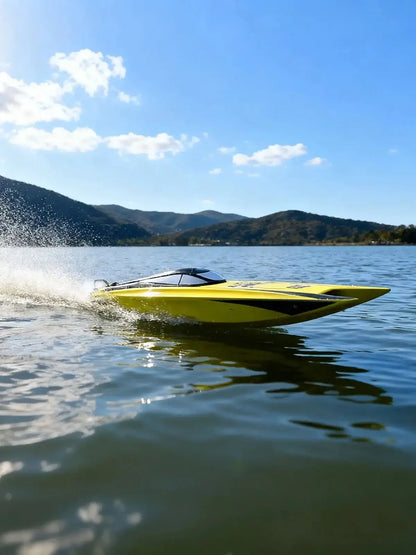 Large Remote Control Boat speeding across the water with mountains in the background under a clear blue sky.