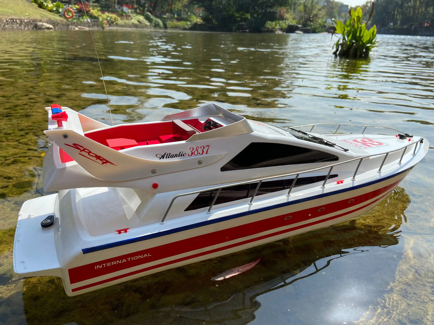 Super large remote control yacht floating on a lake surrounded by greenery.