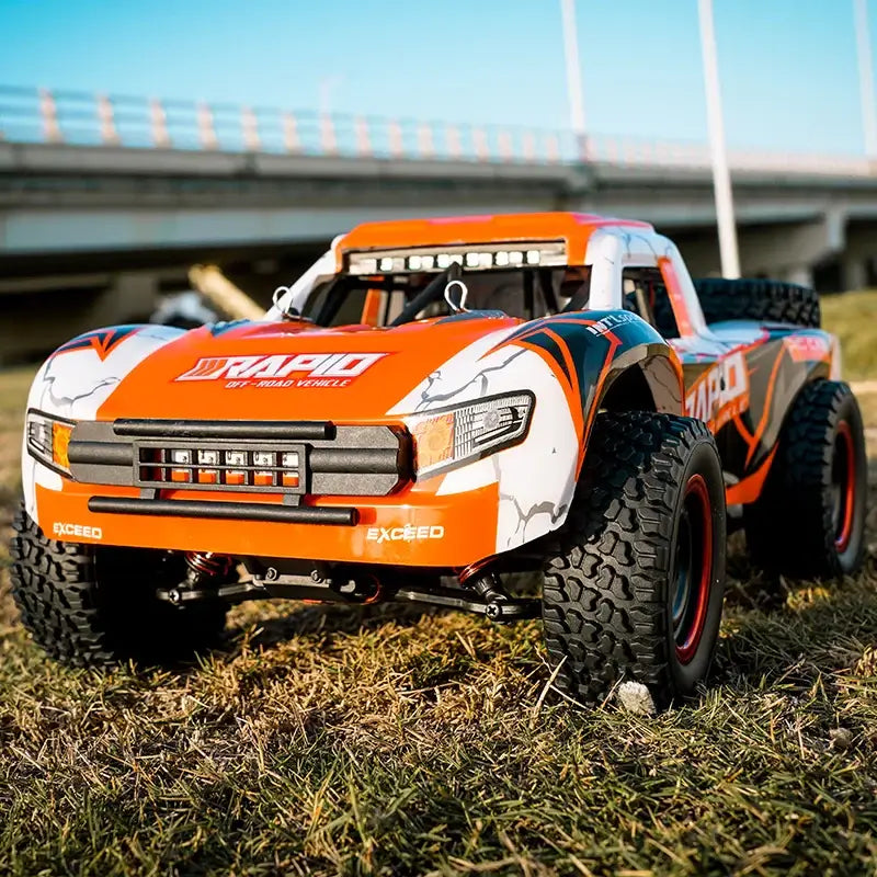 JJRC Q130 RC Car in vibrant orange color, showcasing its off-road capabilities on grass under clear blue sky.