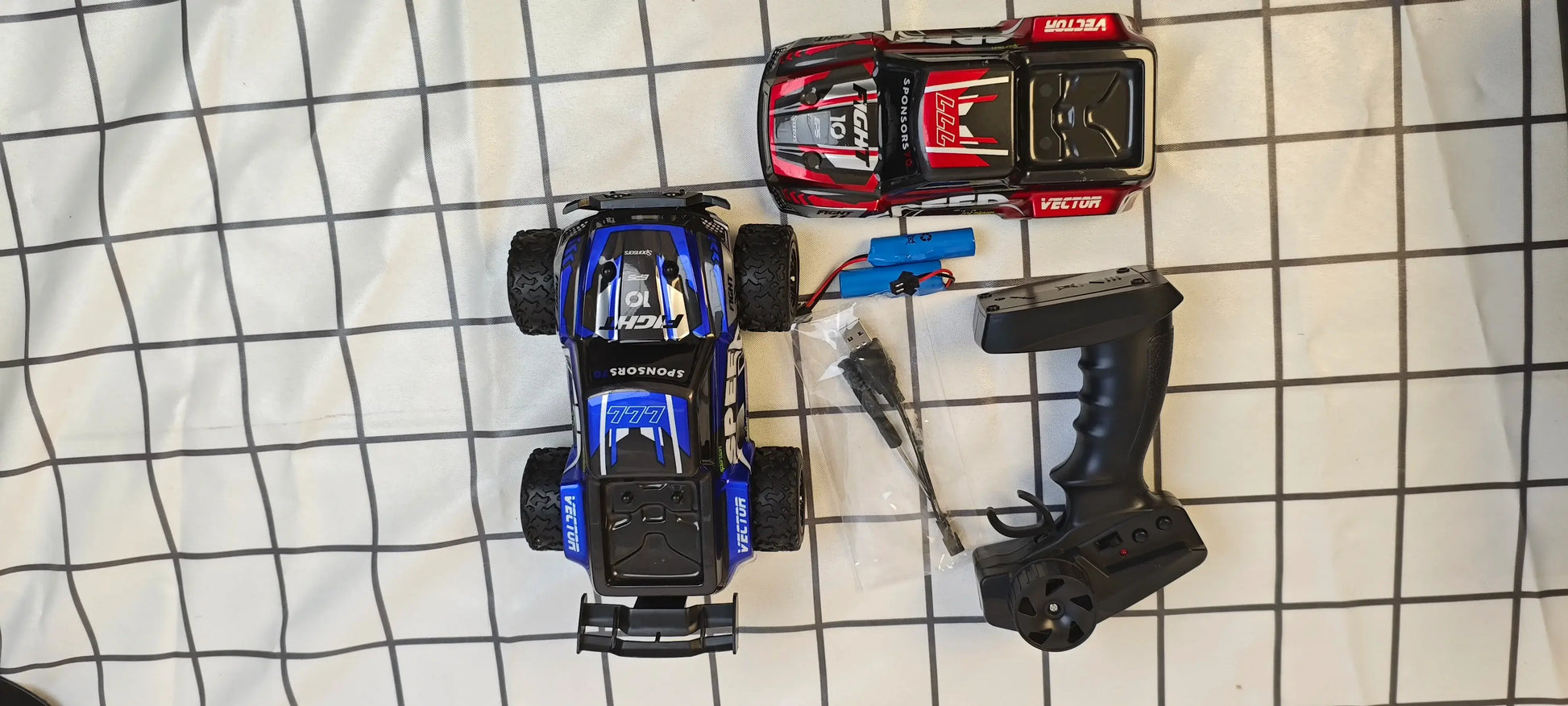 four wheel drive remote control truck displayed with remote control and accessories on a checkered surface.