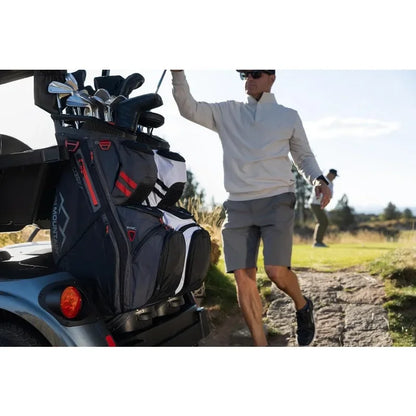 Man walking with Men's C130 Lightweight Cart Golf Bag on a golf cart while another golfer plays in the background.